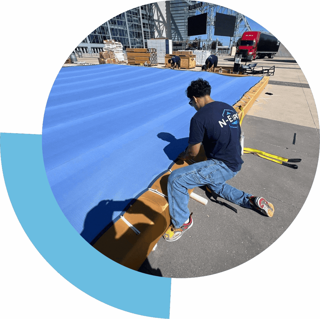 A person kneeling and working on a large blue tarp outdoors.